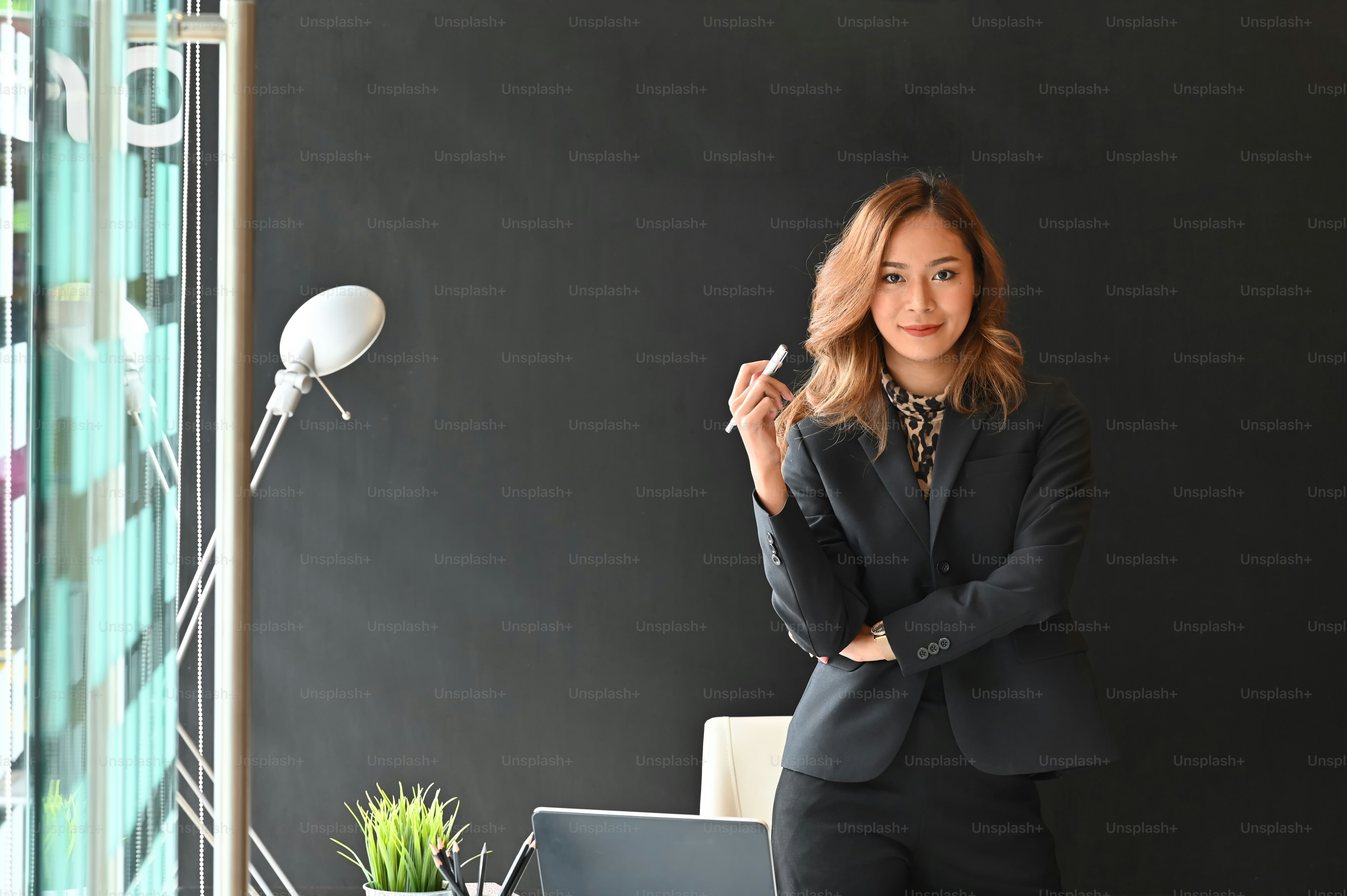 Confidently businesswoman standing on front office desk